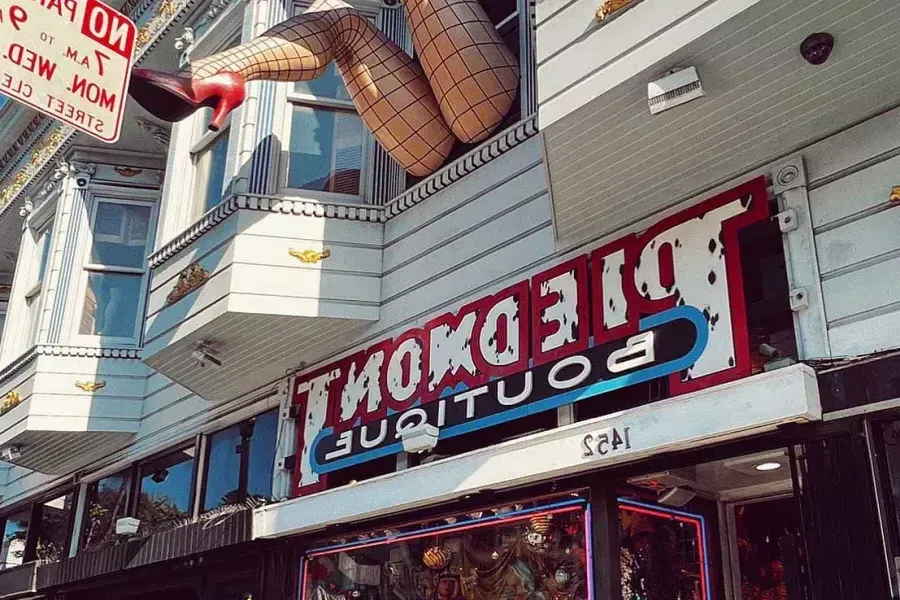 A pair of mannequin legs wearing fishnet stockings hang out of a window over Haight Street at Piedmont Boutique. San Francisco, California.